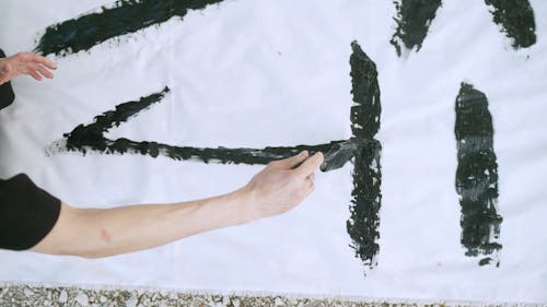 Person Writing Japanese Characters On White Textile