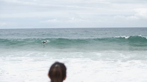 Woman Watching a Man Surfing