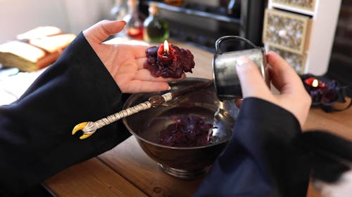 A Person Pouring Rice and Melted Wax on a Bowl of Liquid