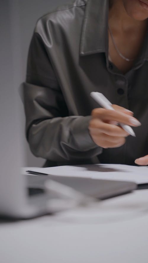 A Woman in Business Attire Writing on Paper