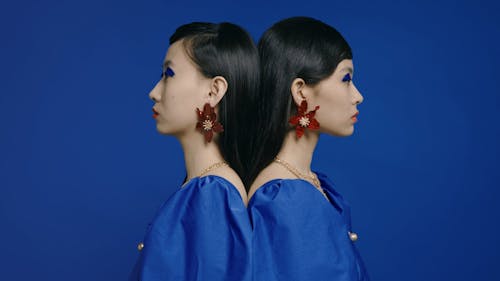 Female Twins Standing Back to Back While Both Looking at the Camera