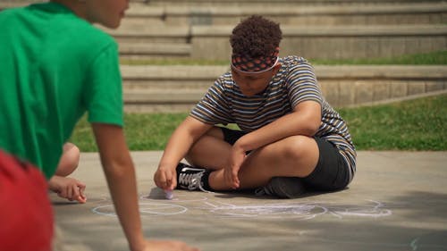 A Little Boy Making Art on the Ground with Chalk