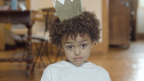 A Young Boy Smiling and Wearing a Paper Crown