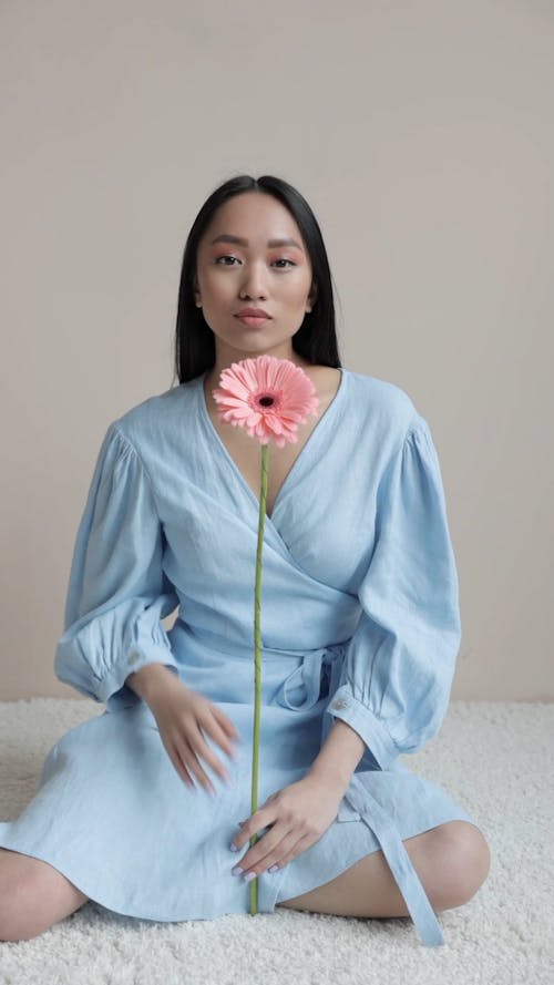 Female Model Wearing a Blue Dress Holding a Pink Flower