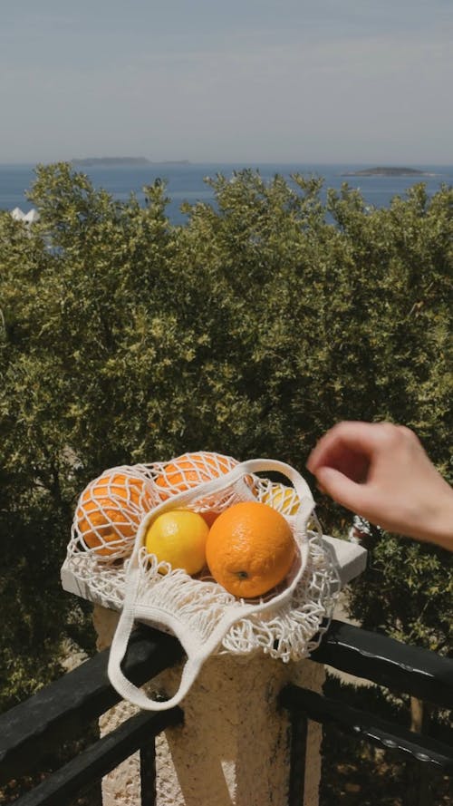 Person Picking Up An Orange From A Basket