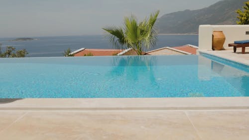 Woman Walking On Poolside Carrying A Basket Of Oranges