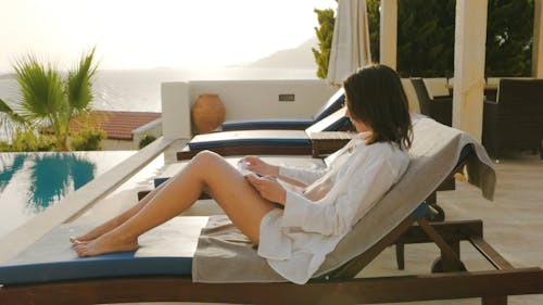 Woman Reading a Book Near the Pool