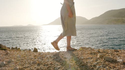 Woman Walking Along A Rocky Seashore