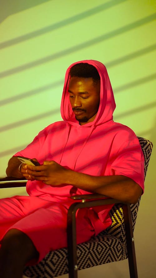 Man Sitting on a Chair While Using Cellphone