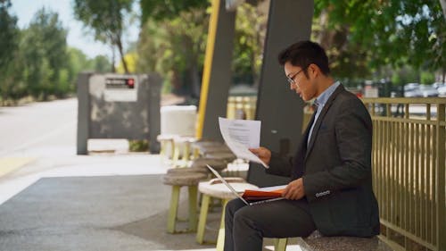 Man Organizing Documents While Sitting In A Bench