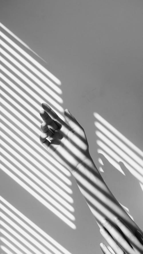 Close up of Hands Against the Shadow of Window Blinds