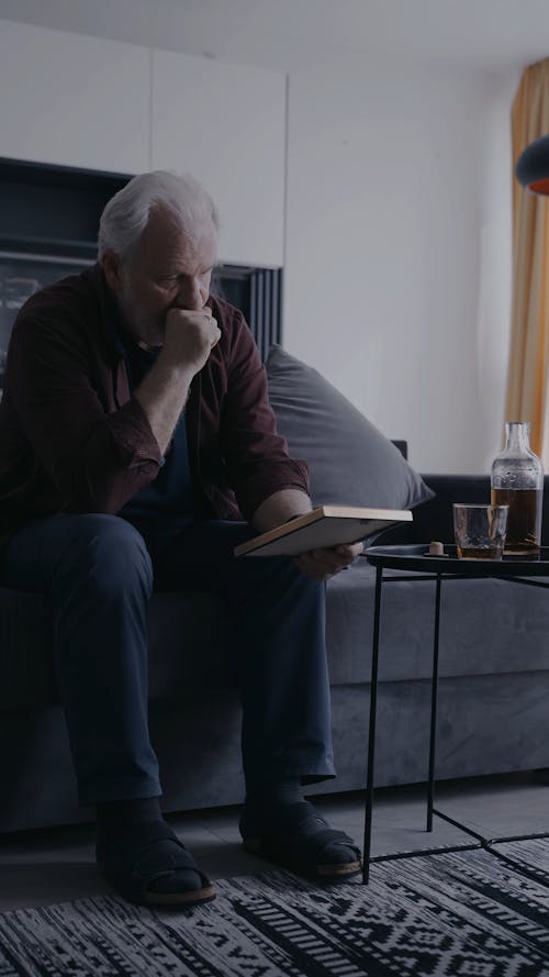 A Sad Elderly Man Looking at a Picture Frame