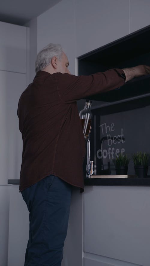 Elderly Man Looking at a Picture Frame and Drinking Liquor