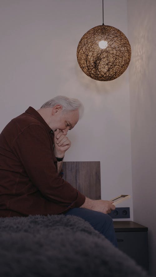Elderly Man Crying while Looking at a Picture Frame