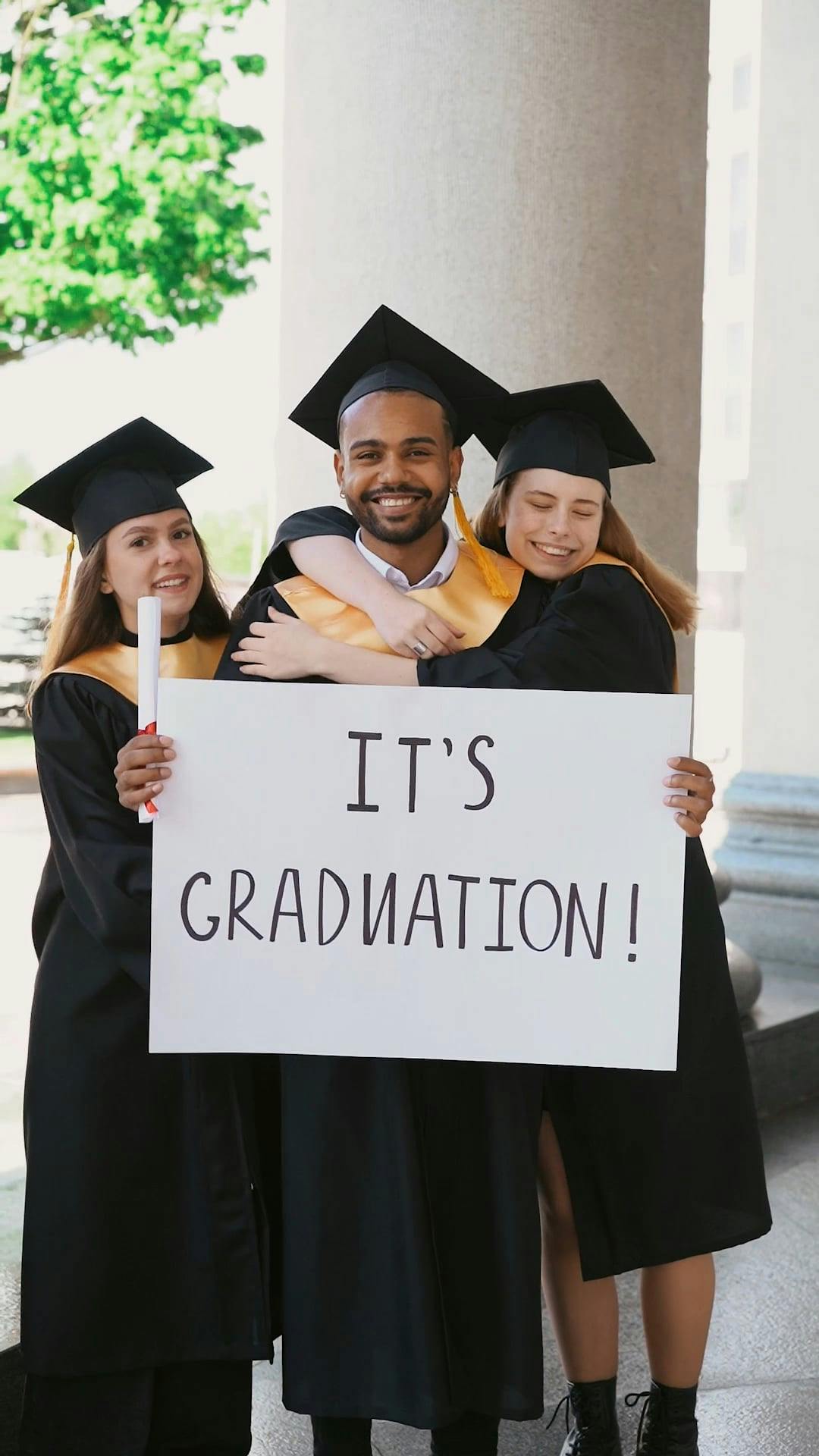 People Wearing Graduation Gown Holding a Banner · Free Stock Video