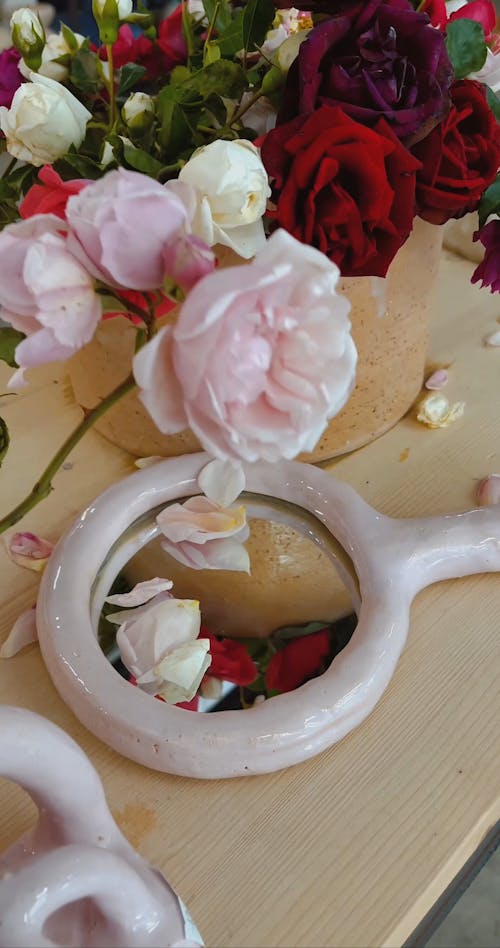 A Person Putting Pink Roses on a Hand Mirror