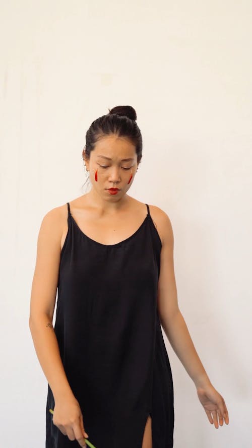 A Woman with Petals on her Face Dancing while Holding a Flower