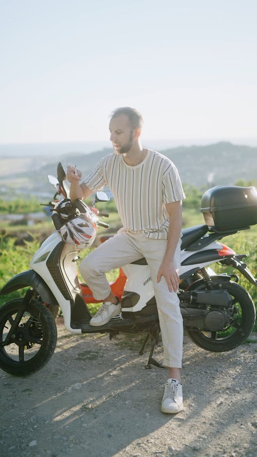 A Man Smoking a Cigarette on a Moped
