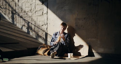 A Homeless Person Eating Bread