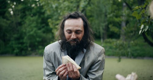 A Homeless Person Eating a Sandwich