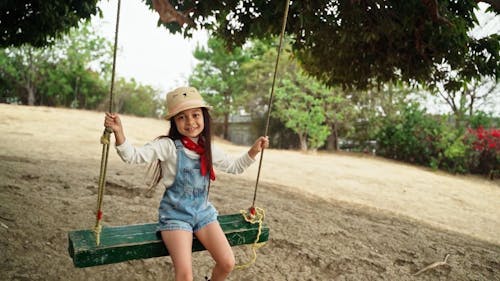 A Girl Sitting on a Swing Under the Tree