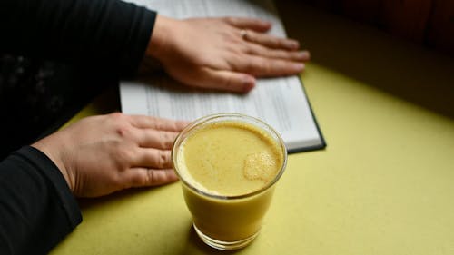 A Person Holding a Drink while Turning Pages