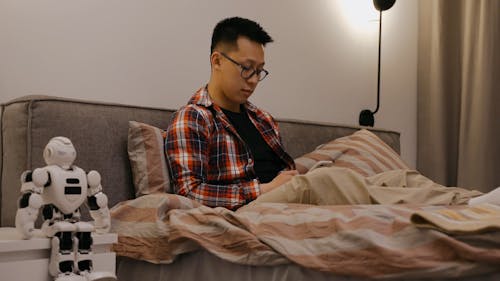 A Man Using a Cellphone in Bed