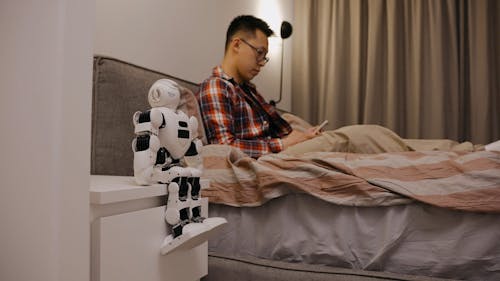 A Man Using a Cellphone in Bed