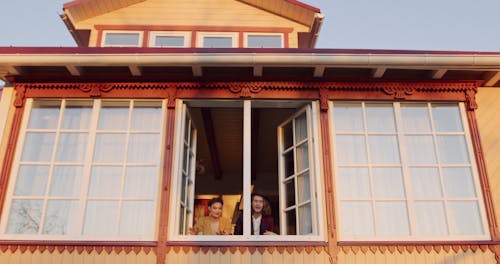 A Young Couple Looking Outside a Window