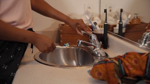 A Person Washing a Toothbrush