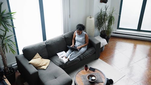 A Woman Sitting on a Couch while using Laptop
