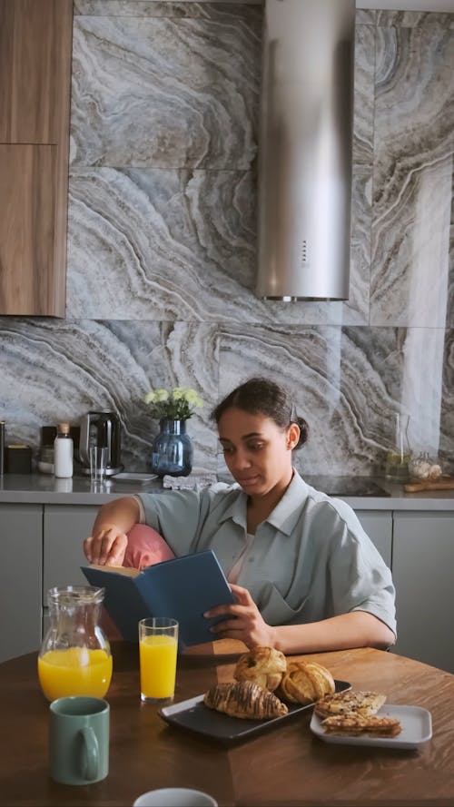 A Woman Reading a Book while Sitting in the Kitchen 
