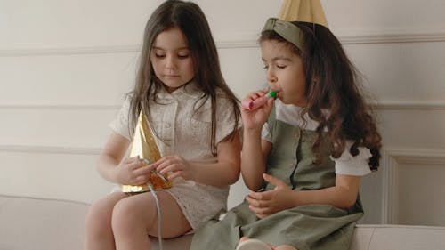 Girls wearing Party Hat and Playing Party Horn