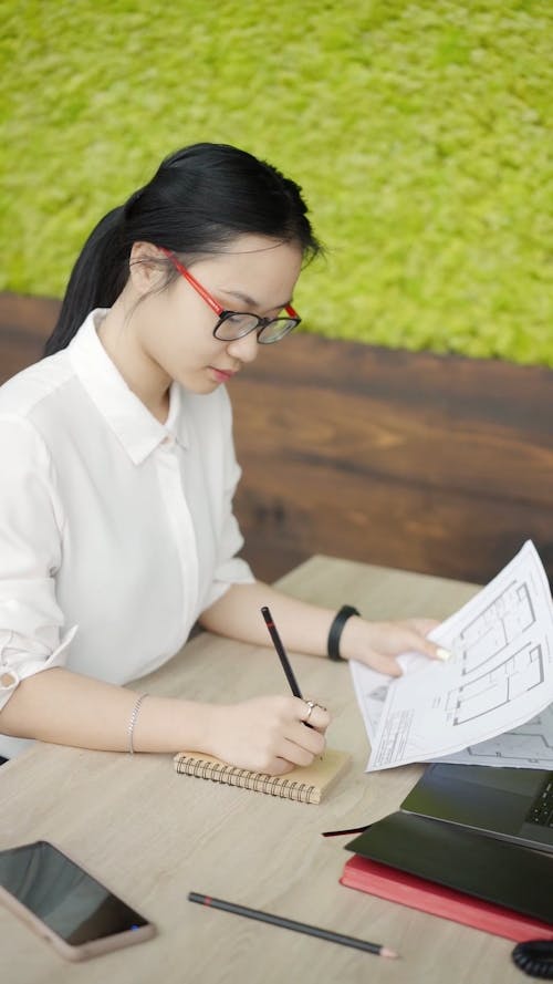 Woman Writing Notes while Working in the Office