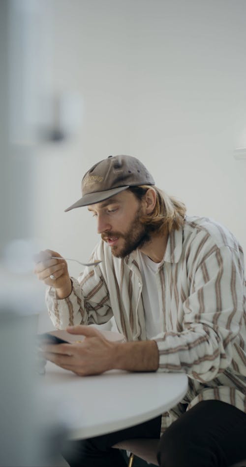 Man Eating while Browsing on his Phone