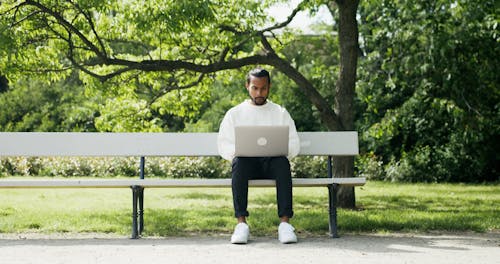 A Man Using a Laptop while Sitting on a Bench