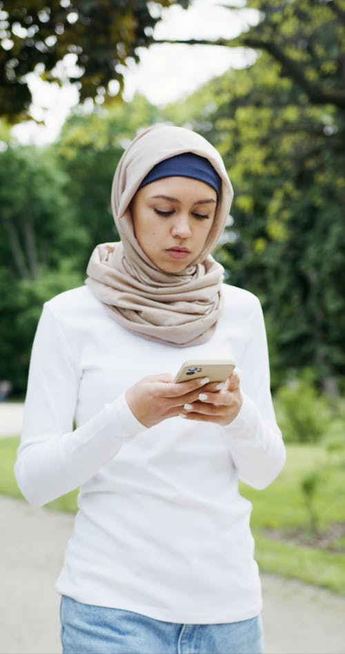 Woman Wearing Hijab Using Cellphone While Walking