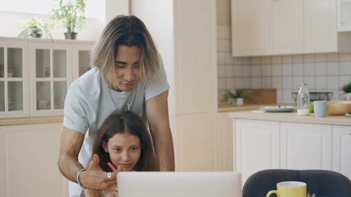 A Man Teaching a Girl How To Use Laptop