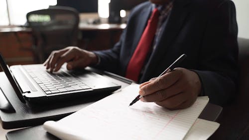 A Person Working at the Computer while Writing