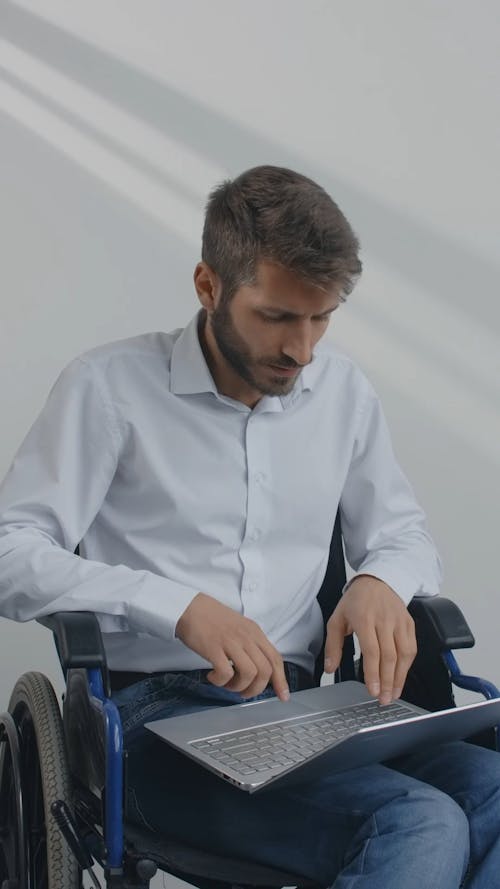 A Man Sitting on Wheelchair while Using His Laptop
