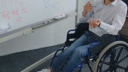 A Man Sitting on Wheelchair while Discussing the Graph