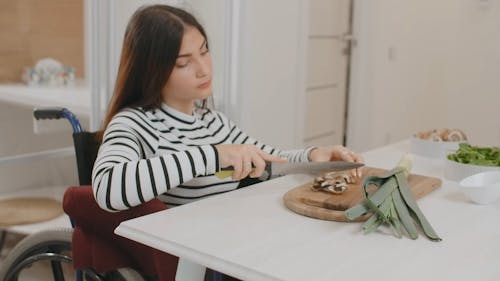 A Woman Slicing Vegetables While Sitting on a Wheelchair