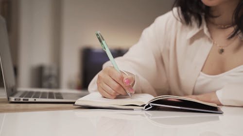 A Woman Writing on a Notebook