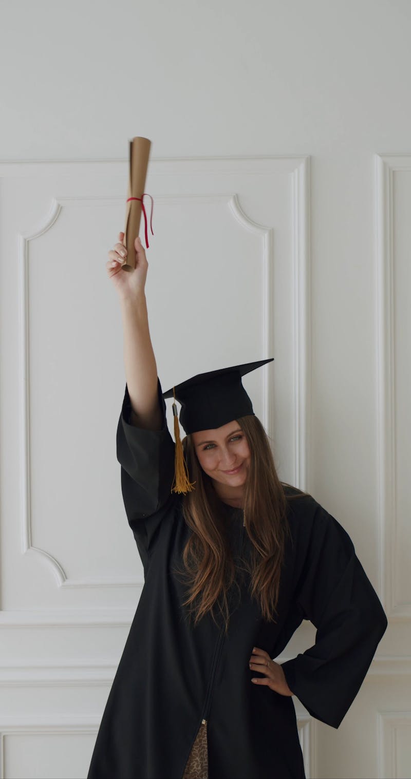A Woman Wearing a Graduation Gown Holding a Graduation Cap and a ...
