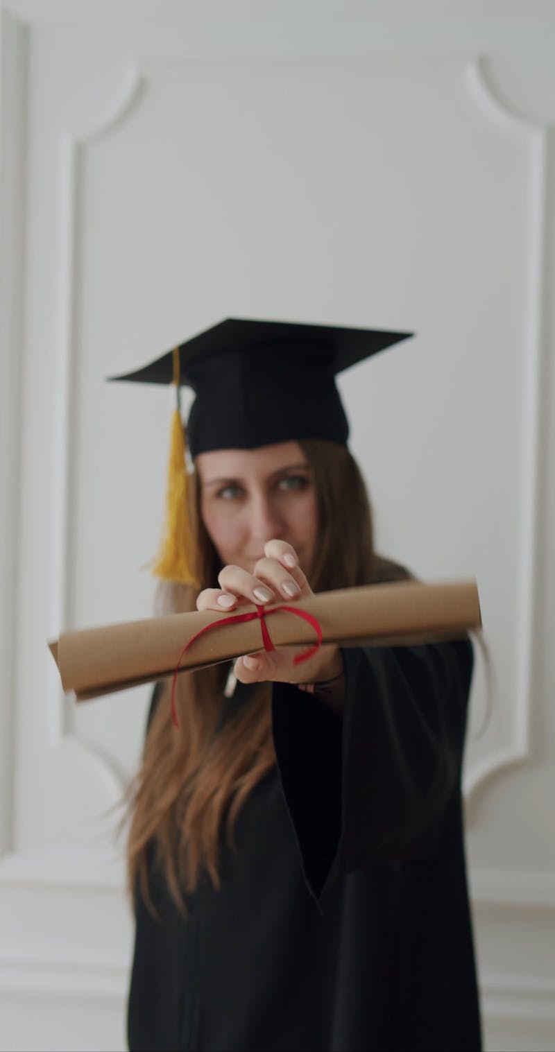A Woman Wearing a Graduation Gown Holding a Graduation Cap and a ...