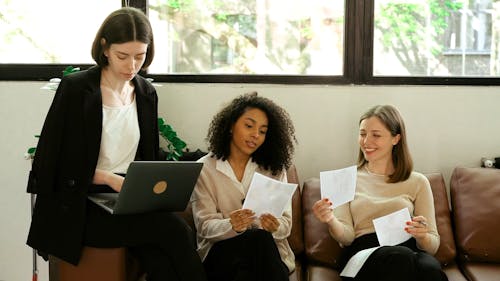 Women Looking at the Photos while their Coworker using Laptop