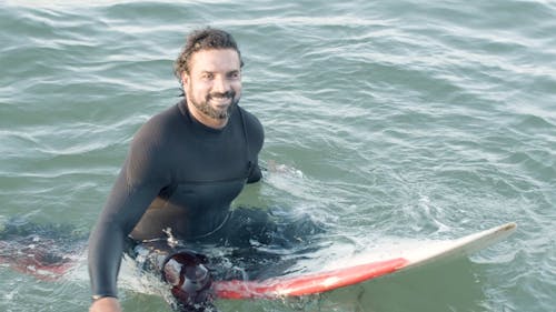 Man Sitting on Surfboard in Water