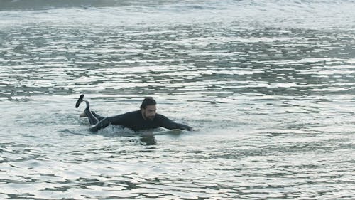 Man in Wetsuit Paddling on Surfboard
