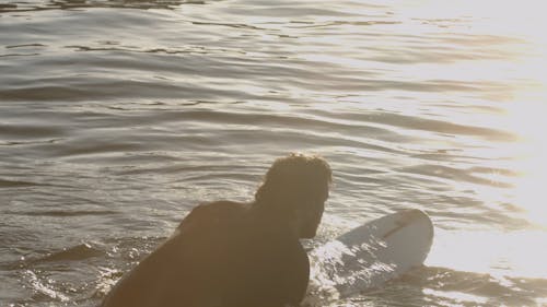 Man Paddling on a Surfboard