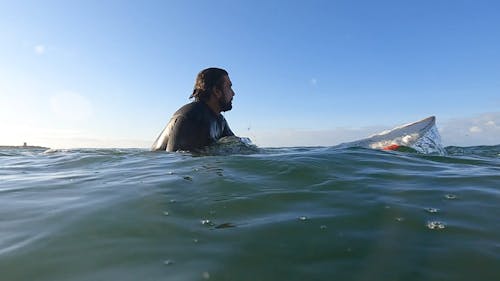 Man Sitting on Surfboard in Water